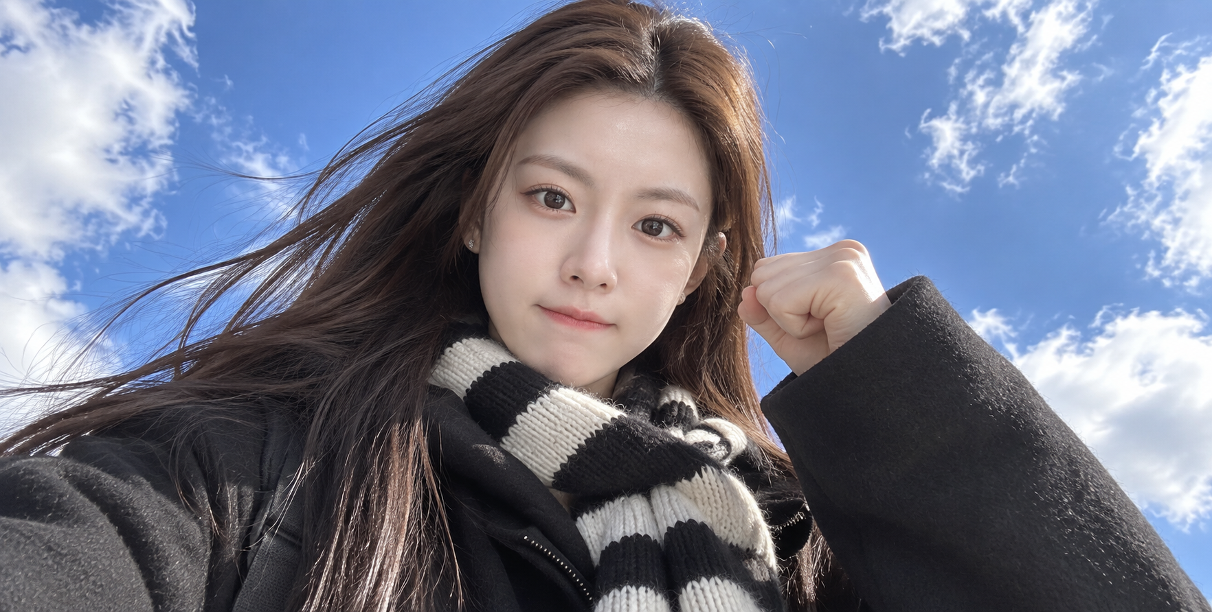 Low-angle selfie of an East Asian beauty posing energetically against a blue sky